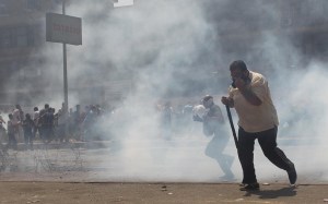 Pro-Mursi supporters run from tear gas during clashes with security forces around the area of Rabaa Adawiya square, where the protesters are camping, in Cairo