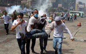 Supporters of deposed Egyptian President Mohamed Mursi carry a protester injured during clashes with riot police and army at around the area of Rabaa Adawiya square, where they are camping, in Cairo